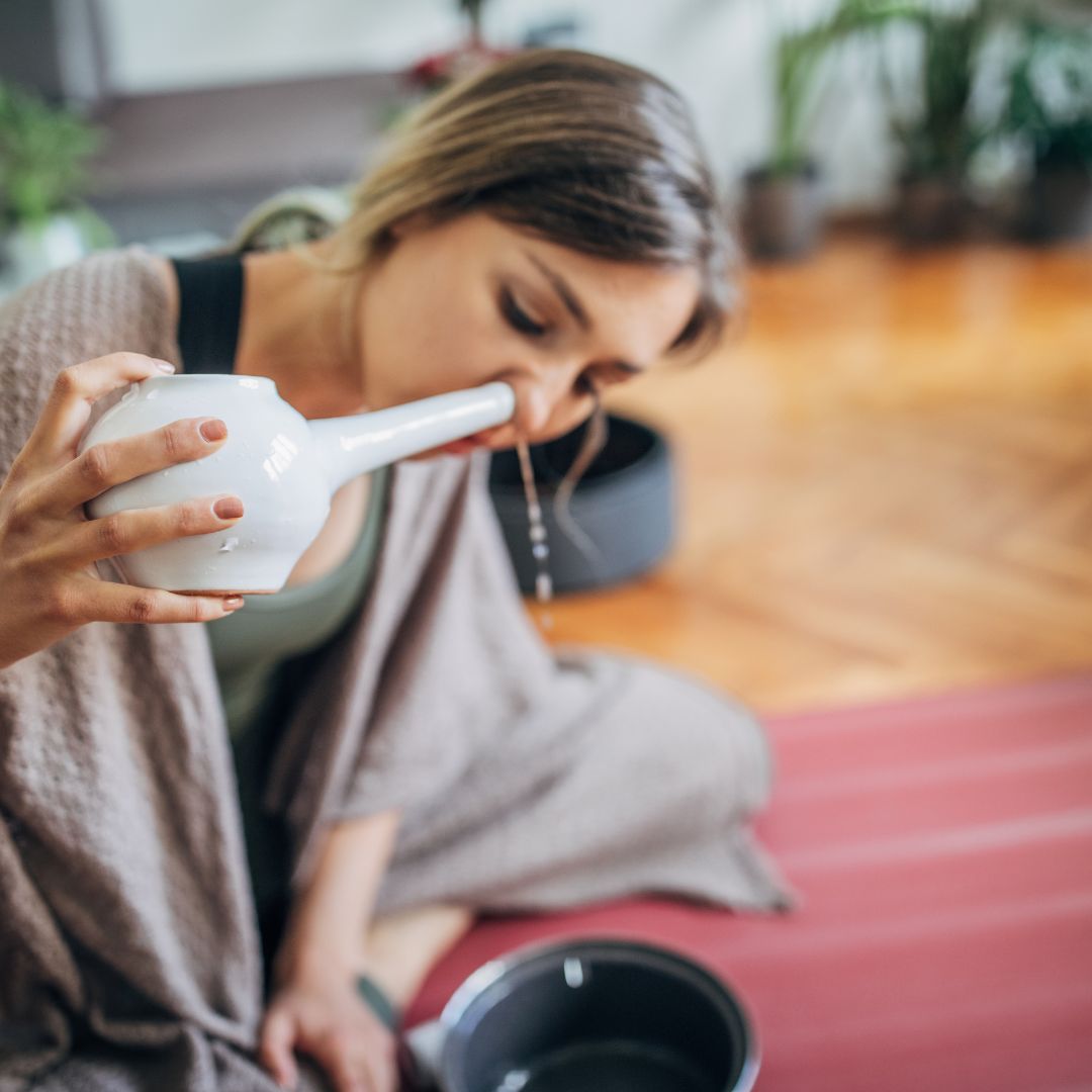 woman flushing her sinuses with a Neti pot